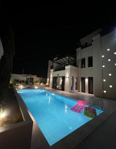 a swimming pool in front of a house at night at Zerø Føur DeadSea in Sowayma