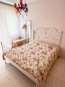 a white bed in a bedroom with a chandelier at The Early Bird - Cosy 2-Floor House with Garden in Alexandroupoli