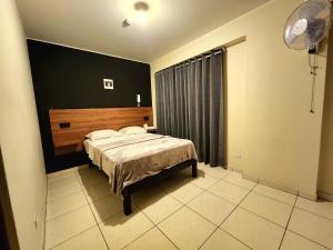 1 dormitorio con cama y pared negra en HOSTAL IMH, en Lima
