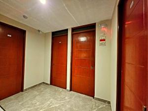 un pasillo con 3 puertas de madera en un edificio en HOSTAL IMH, en Lima
