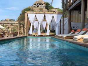 a swimming pool with chairs and a house at Hotel Nude Zipolite & beach club in Zipolite