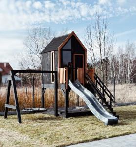 a playground with a slide and a play house at Koncept domki in Jantar