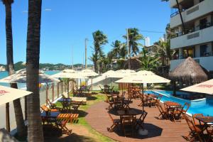 a group of tables and chairs with umbrellas next to a pool at Apartamento a Beira Mar no Flat Elegance in Natal