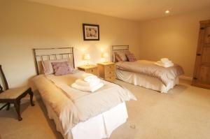 a bedroom with two beds and a chair in it at Rock Moor House B&B in North Charlton