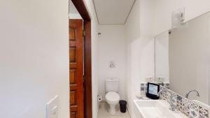 La salle de bains est pourvue de toilettes, d'un lavabo et d'un miroir. dans l'établissement Studio 7 Pinheiros by Oba, à São Paulo