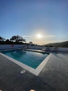 a swimming pool with a sunset in the background at Villa George Sea View with pool - Triopetra in Triopetra