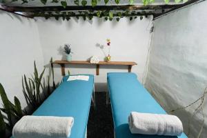 a room with two blue beds and a table at Hermoso Glamping Karpatos in Barichara