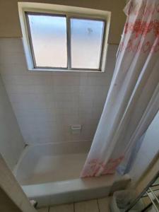 La salle de bains est pourvue d'un rideau de douche et d'une fenêtre. dans l'établissement Lovely Single Apartment, à Los Angeles