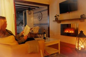 una mujer sentada en un sofá leyendo un libro en Furnas Nook en Furnas