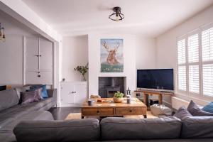 ein Wohnzimmer mit einem Sofa und einem TV in der Unterkunft Captain's Keep in Lymington