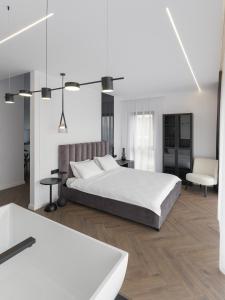 a white bedroom with a bed and a chair at Evo Residence Panoramic in Cluj-Napoca