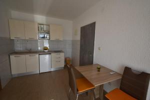 a small kitchen with a wooden table and a dining room at Denjak Apartments in Kornić