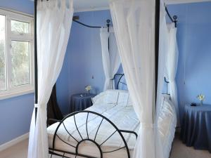 a bedroom with a canopy bed with white curtains at Rowan Cottage-80119 in Catcleugh