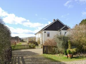 a house with a fence next to a driveway at Rowan Cottage-80119 in Catcleugh