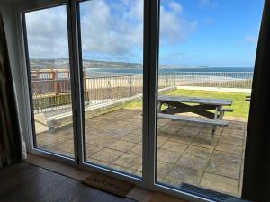 ein Blick auf das Meer aus einem Fenster mit einem Picknicktisch in der Unterkunft Treleigh in Hayle