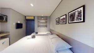2 camas en una habitación pequeña con 3 cuadros en la pared en Studio 1 Pinheiros by OBA, en São Paulo