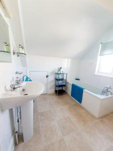 een badkamer met een wastafel en een bad bij Cleave Court Guest House in Llandudno