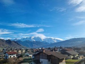 una ciudad con montañas cubiertas de nieve en el fondo en Vue magique en Sallanches