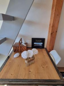Habitación con mesa de madera y 2 flores blancas. en Vue magique en Sallanches