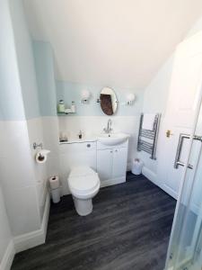 een witte badkamer met een toilet en een wastafel bij Cleave Court Guest House in Llandudno