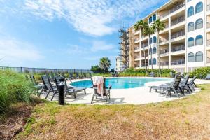 a swimming pool with chairs and a table and a building at Seascape 315 - Oceanfront Condo Overlooking Pool in Isle of Palms