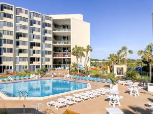 a hotel with a swimming pool and chairs and a building at Top of The Gulf 306 in Panama City Beach