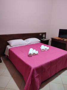 a pink bed with three pairs of shoes on it at Le Due Palme in Marsala