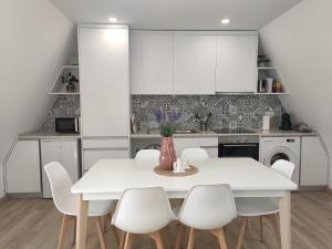 a white kitchen with a white table and chairs at Aveiro Ria House E in Aveiro