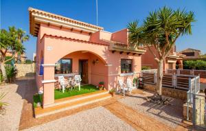 a pink house with a yard with chairs at Gorgeous Home In Isla Plana With Wifi in Isla Plana +24 photos