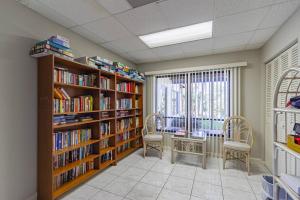 a library with two chairs and shelves of books at Yellow Pine Duplex Close to Pool & Tennis in Sarasota