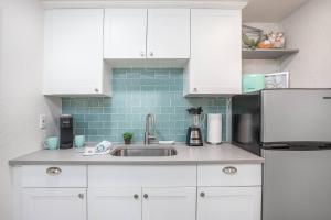a kitchen with white cabinets and a sink at Pelican Gardens Studio 3 on Lido Key in Sarasota