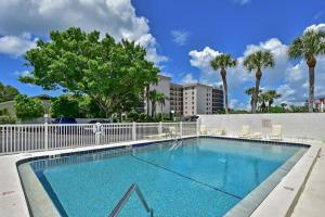 a swimming pool with a fence and palm trees at Pelican Gardens 7 By Lido Beach in Sarasota