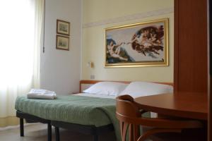 Un dormitorio con una cama con una mesa y una pintura en Hotel Parco Fellini, en Rímini