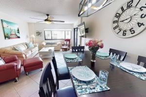 a dining room and living room with a table and a clock at Siesta Sands Beach Resort Gulf View in Sarasota
