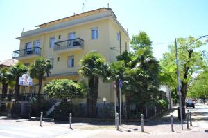 un edificio giallo con palme di fronte di Hotel Parco Fellini a Rimini