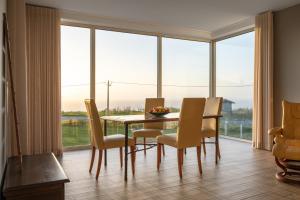 une salle à manger avec une table, des chaises et une grande fenêtre dans l'établissement SilverSide Holidays, à Caldas da Rainha