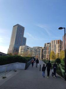 a group of people walking down a sidewalk in a city at City View 1 Bedroom Flat in London
