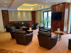 a lobby with leather chairs and a flat screen tv at Hotel Hanseatischer Hof in Lübeck
