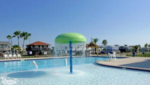 a swimming pool with a green umbrella in the water at Peggys Hideaway in Galveston