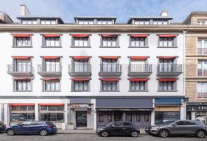 een wit gebouw met rode bogen op de ramen bij Sure Hotel By Best Western Lorient Centre in Lorient