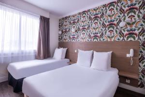 two beds in a hotel room with a wallpaper at Sure Hotel By Best Western Lorient Centre in Lorient