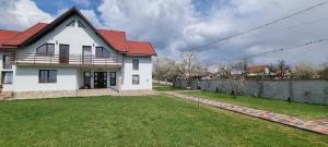 Casa blanca con techo rojo y patio en Pensiunea Casa Mădă, en Baia de Fier