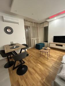 een woonkamer met een tafel en stoelen en een televisie bij ApartmanM&M in Banja Luka