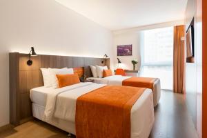 2 letti in una camera d'albergo con arancio e bianco di Libre Hotel, BW Signature Collection by Best Western a Lima