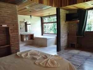 a bedroom with a large bed and a bathroom at Pousada Pizzaria do Vale in Visconde De Maua