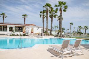 - une piscine bordée de chaises et de palmiers dans l'établissement THE CLUB - Accommodation - Dining - Events, à San Miguel de Abona
