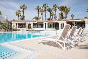 Un grupo de tumbonas junto a una piscina. en THE CLUB - Accommodation - Dining - Events, en San Miguel de Abona