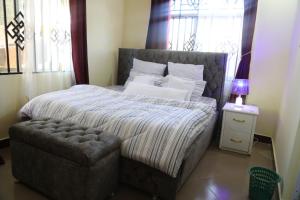 a bedroom with a large bed and a chair at Lovely Pearl Intercity Homes in Dar es Salaam