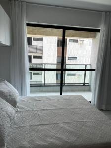 a bedroom with a bed and a large window at Beira-Mar Boa Viagem - Ivone Asfora by Bnb Flex in Recife