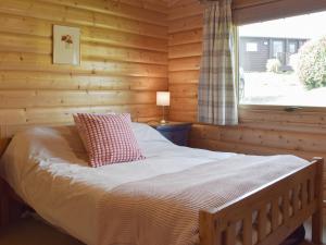 a bed in a log cabin with a window at Cwm Gain in Llanrian